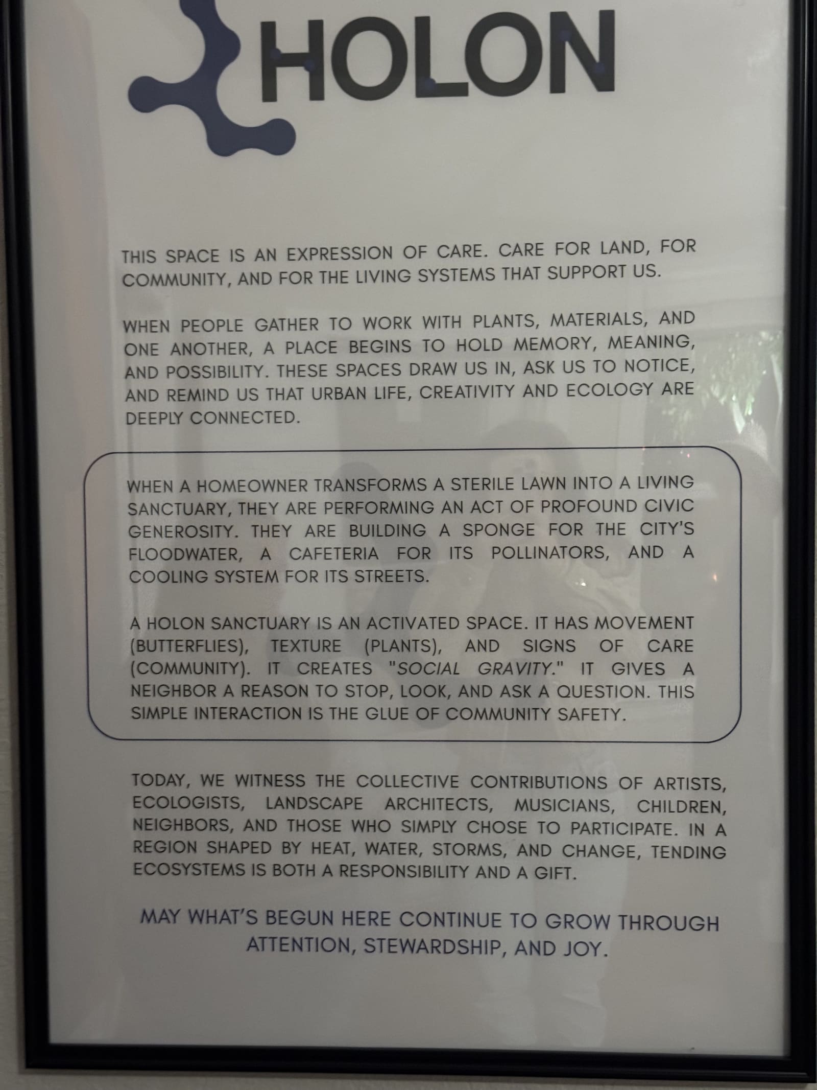 The framed Holon opening statement hanging on a white wall