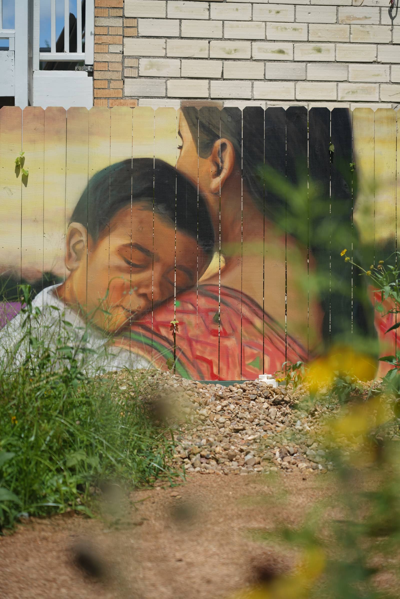 Close view of the mural, a mother and sleeping child painted on a wooden fence
